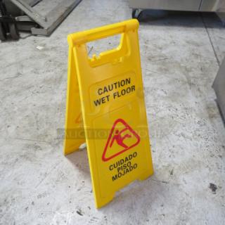 Yellow caution wet floor sign in new condition, with English and Spanish text.