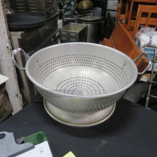 15x7 inch aluminum colander with sturdy handles, perforated for drainage. Used condition. Ideal for kitchen tasks.