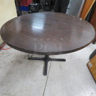 Solid wooden table top, 1.5-inch thick, on pedestal base, 52x52x30 inches, dark finish, used condition.