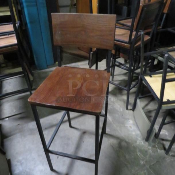 Black metal and wooden bar height chair with footrest, sturdy frame, used condition, suitable for kitchen or bar setting.