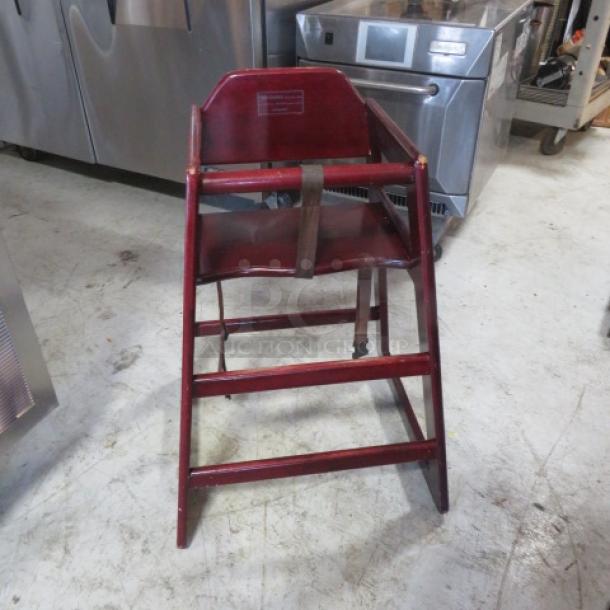 Wooden high chair with safety straps, rich brown finish, sturdy frame. Ideal for toddlers, good condition.