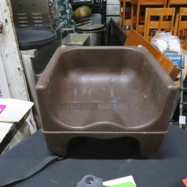 Brown dual-sided booster seat, sturdy plastic, lightly worn, no visible labels. Ideal for child seating.