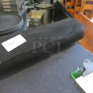 Mega roll of black bar netting on table, tag labeled "164". Netting is rolled, durable, used for secure bar setups.