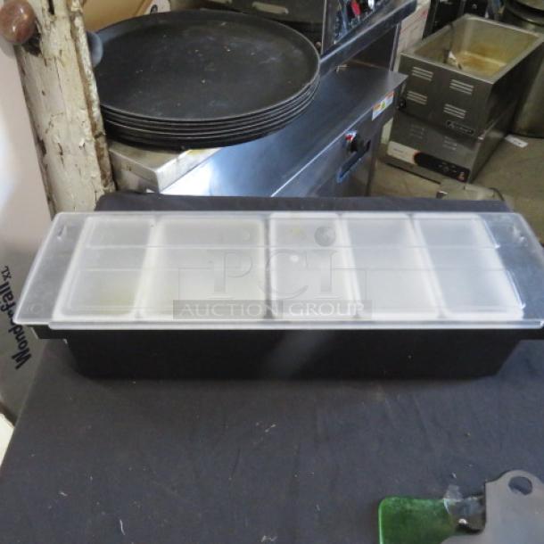 Domed bar center with multiple compartments, black base, and clear lid. Used condition, ideal for organizing bar supplies.