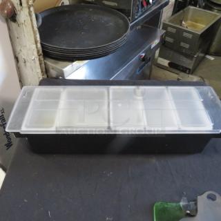 Domed bar center with multiple compartments, black base, and clear lid. Used condition, ideal for organizing bar supplies.
