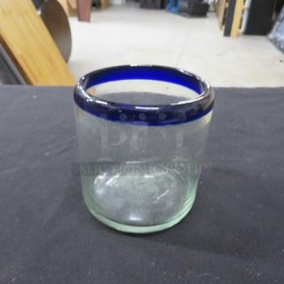 Clear glass rocks glass with blue rim, labeled 8XBID. Slightly worn condition. Simple, elegant design.