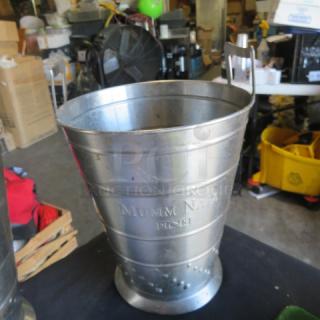 Stainless steel wine bucket with "Mumm Napa" branding, in used condition. Features sturdy handles and a tapered design.