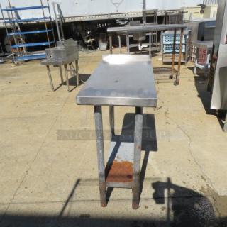 Stainless steel table with under shelf, 15x30x36 inches, used condition with visible rust on legs, sturdy construction.