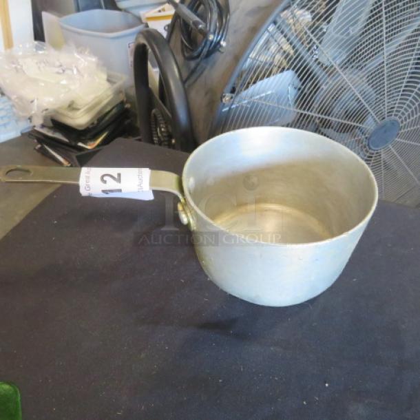 1.5 quart aluminum sauce pan with long handle, gently used. Auction tag marked "12" attached to handle.