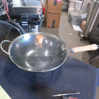 New wok with lid, featuring a wooden handle and knob. Includes a glass lid. Excellent condition, no visible defects.