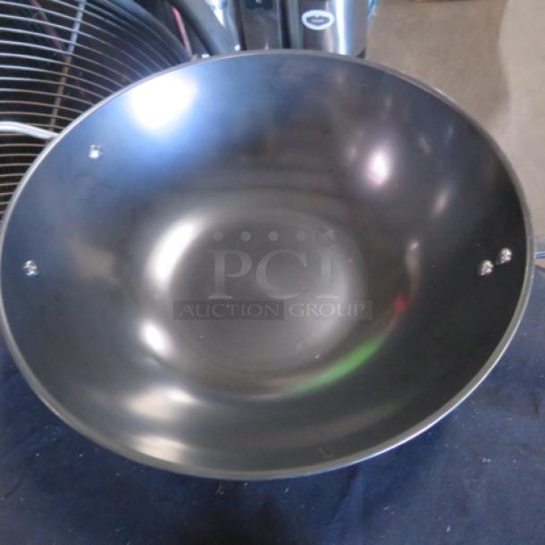 New wok with lid, black, steel construction, smooth finish, no visible markings or labels, pristine condition.