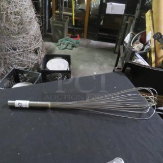 Stainless steel whip with multiple wires, used condition, visible label marked "87", sturdy handle, ideal for mixing.