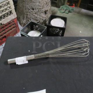 Stainless steel whip with a robust handle, resting on a table. Appears in good condition, potential kitchen tool.