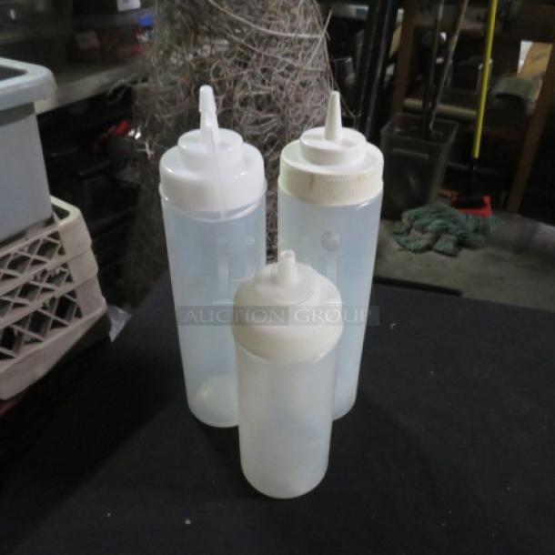 Assorted squeeze bottles in varying sizes; clear plastic with white caps, suitable for condiments or sauces.