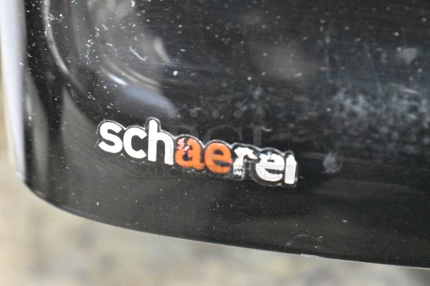 Schaerer Coffee Art Plus commercial espresso machine logo on black metal surface; 120-208/240V, 1 Phase.
