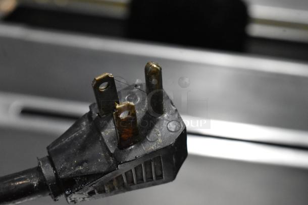 Damaged power plug with visible wear on prongs and corrosion. Black casing shows signs of use and fraying.
