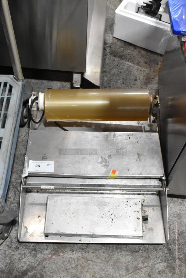 Metal countertop wrapping station, model 5000156, 115 volts, 1 phase, showing wear, includes roll holder and scraps tray.
