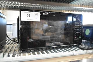 2024 Mainstays MS8436127995-01 Metal Countertop Microwave Oven in used condition. Features control panel and auction tag.