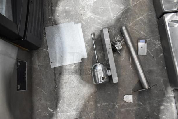 Taylor 340-27 stainless steel frozen beverage machine parts on concrete floor, including metal panels and tubes, for commercial use.