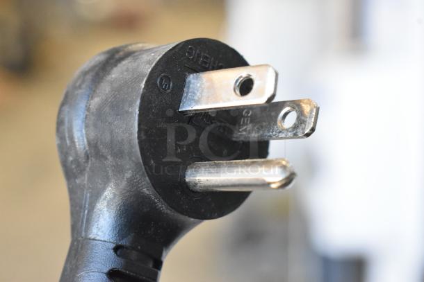 Close-up of a plug for a 2021 True TSCI-600R-G-PH commercial cooler. Black with three prongs, 115 volts compatibility.