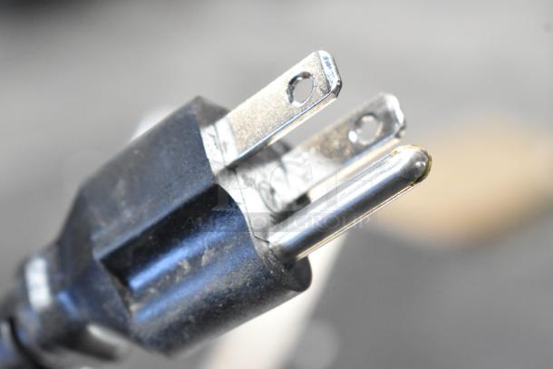 The image shows a close-up of a three-prong electrical plug, typically used for appliances.