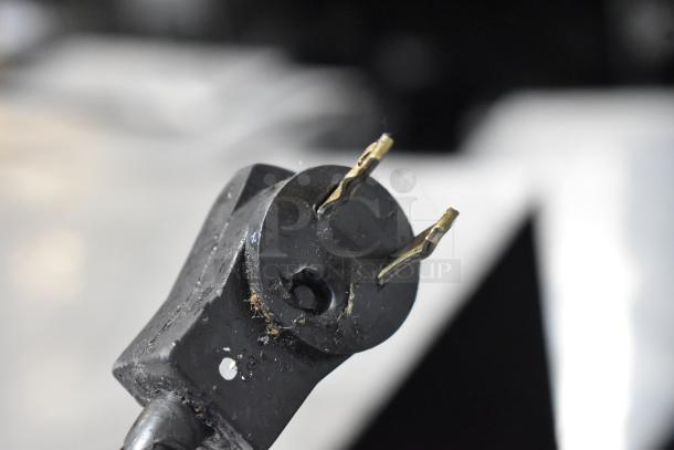 Close-up of a black electrical plug for the Beverage Air SPE48-18M-HMP prep table, showing worn prongs and some debris.