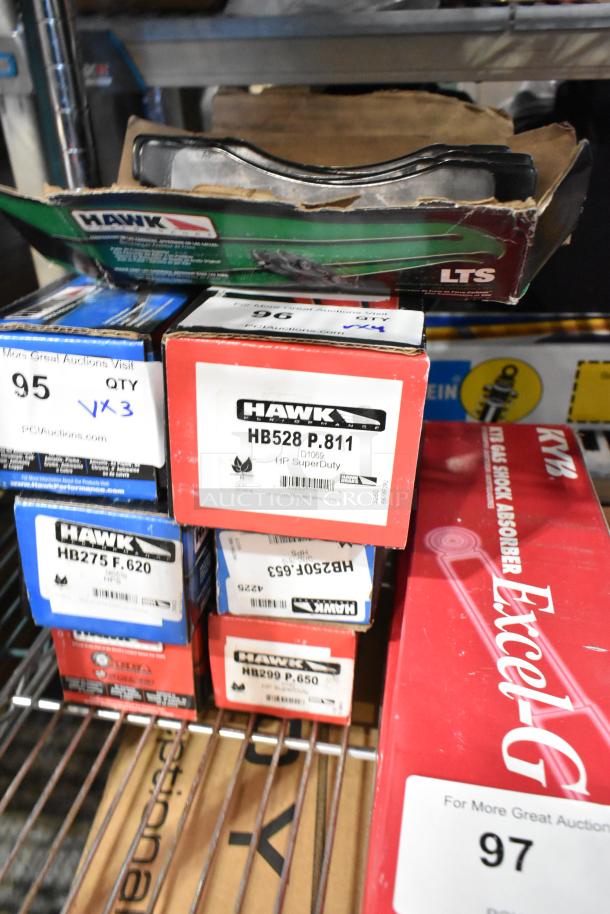 Three new Hawk brake pad boxes, models HB528 P.811 HP SuperDuty, HB275 F.620, and HB299 P.650, on a metal shelf.
