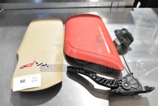 4 items including Grand Sport pad; red and tan covers with racing logos, plastic part; auction tag "98 QTY 4X".