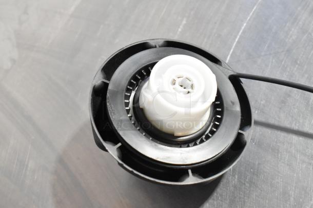 Black plastic spool component with white central mechanism, possibly a part of a larger device. Good condition, details unclear.