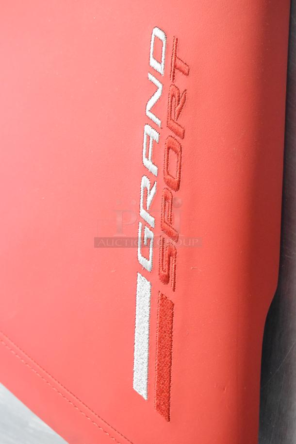 Red Grand Sport pad with embroidered logo, pristine condition. Part of a set of four diverse auction items.