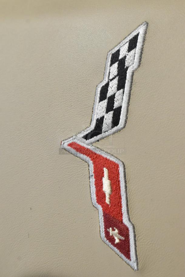 Embroidered Grand Sport logo on beige pad, featuring a black and white checkered flag and red emblem.