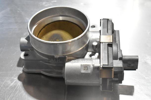 Metal unit featuring a circular opening, made of gray metal, in good condition. Visible barcode label on the side.
