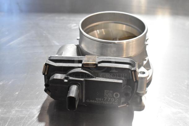 Metal unit featuring a circular metal top and a black plastic base. Labels show codes "12617792" and "GJB64037028 17100."