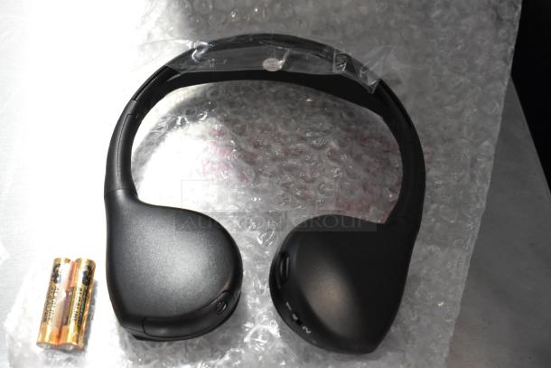 Black wireless headphones with bubble wrap packaging, accompanied by two AA alkaline batteries.