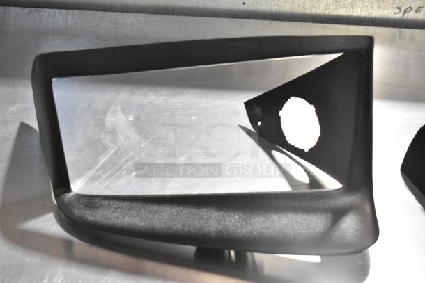 Alt text: Automotive black vent and license plate frame, in good condition, on a metallic surface.