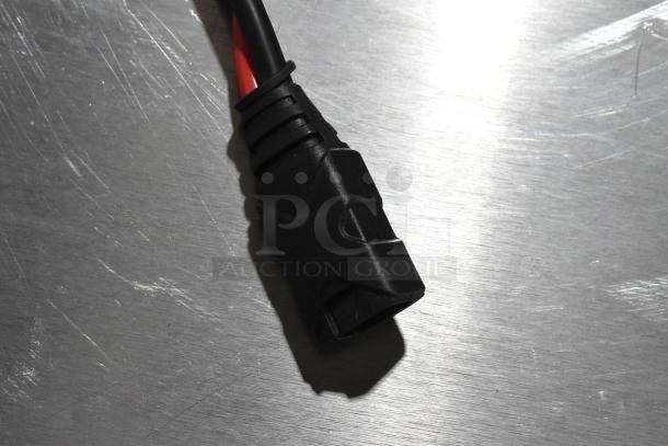 Black electrical connector with a red and black cable on a scratched metal surface. Part of the GB40 Genius Boost auction lot.