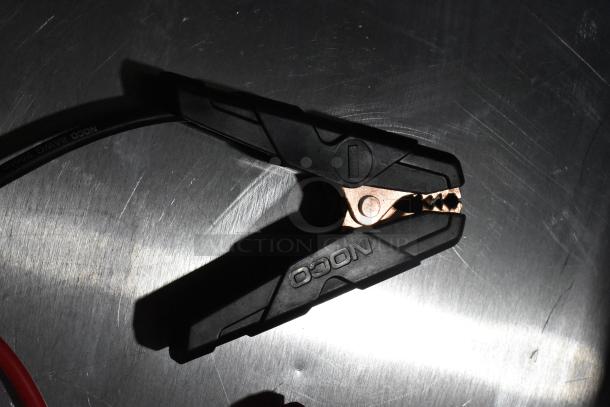 NOCO GB40 Genius Boost battery clamp, black with copper teeth, on metal surface. Key item in a two-item auction package.