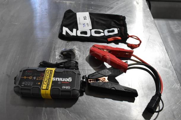 Noco GB40 Genius Boost 12V jump starter, accessories, and bag; includes caution label. Appears in good condition.