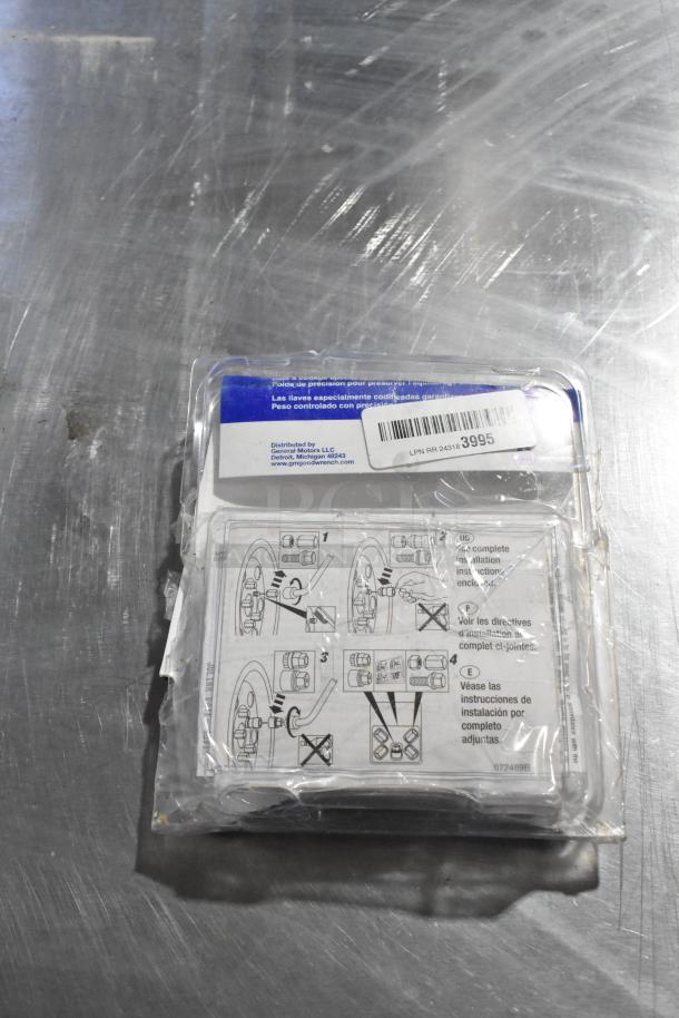 Plastic package with GM wheel locks, instructions in multiple languages, and barcode. Condition: sealed, slight packaging wear.