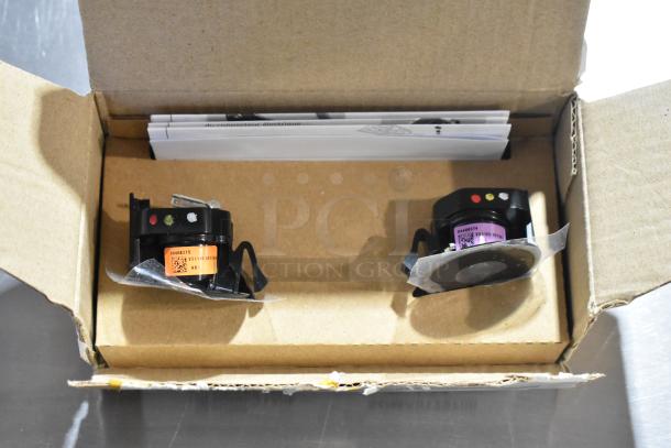 Box containing LED puddle light kit with two units, visible labels with QR codes, and attached instructions.