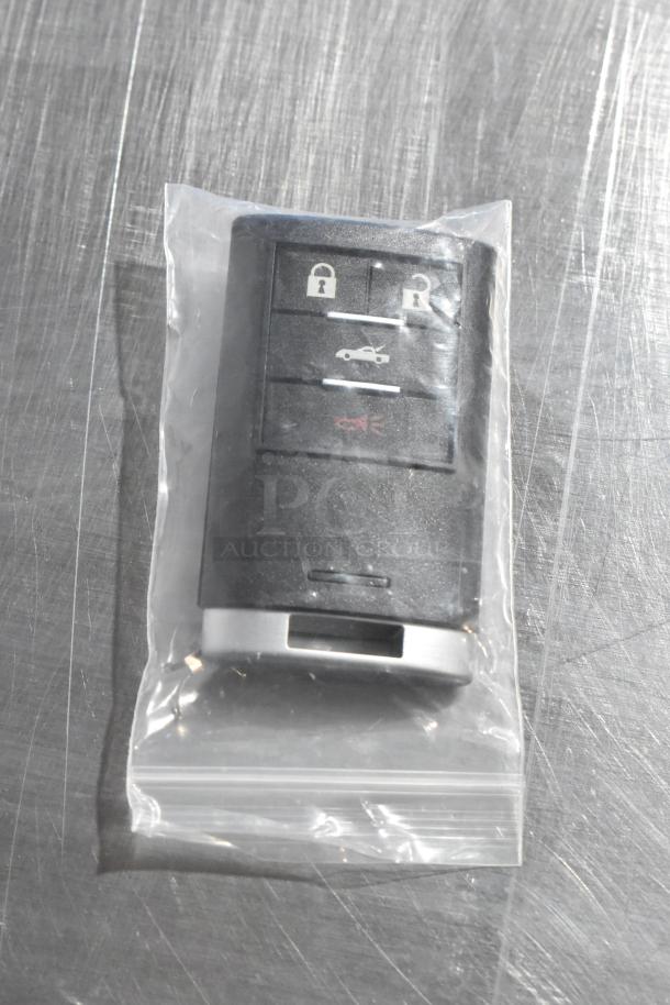Sealed black key fob with lock, unlock, trunk, and panic buttons, in clear plastic bag.