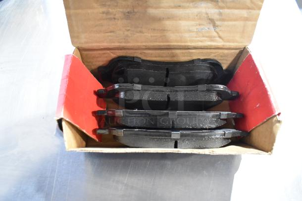 Open box showing several black ceramic brake pads neatly stacked. Condition appears new.