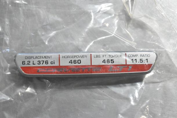 Corvette LT1 emblem showing specs: 6.2L 376 ci, 460 HP, 465 lb-ft torque, 11.5:1 comp ratio; in clear packaging.