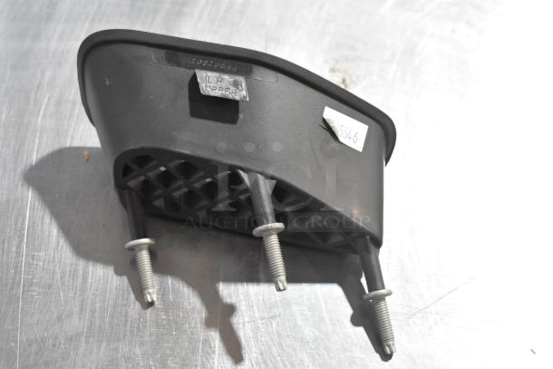 Four automotive parts, including a Corvette LT1 piece and GM Brake Light, labeled LH Upper and GM 25664746, shown on a metal surface.