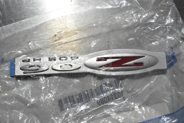 GM 90Z logo on metallic badge, part code X21-116-D1, in sealed plastic packaging with visible barcode and branding.