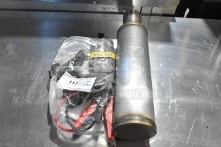 Magnavox MF Exhaust and Noco GB40 Genius Boost in plastic bag. Includes label with auction details. Mild wear visible.
