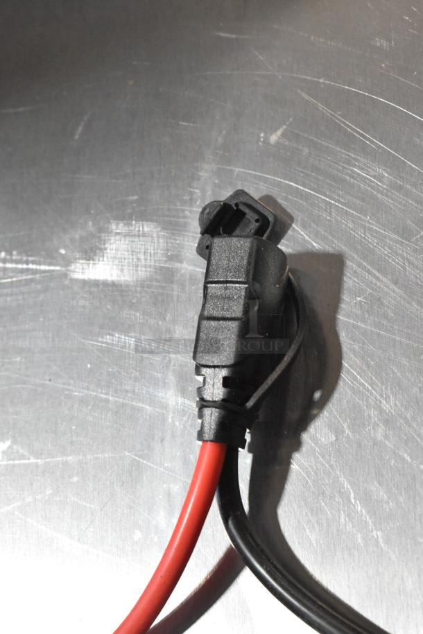 Close-up of Noco GB40 Genius Boost cables with red and black wires on a metallic surface.