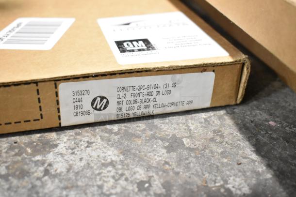 Cardboard box labeled "Corvette 2PC 97/04" front mats with GM logo, black color, new with minor scratches.