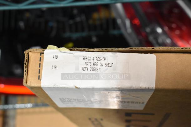 Cardboard box marked "Rebox & Reship," containing new Corvette and Silverado floor mats, ref# 2453311.