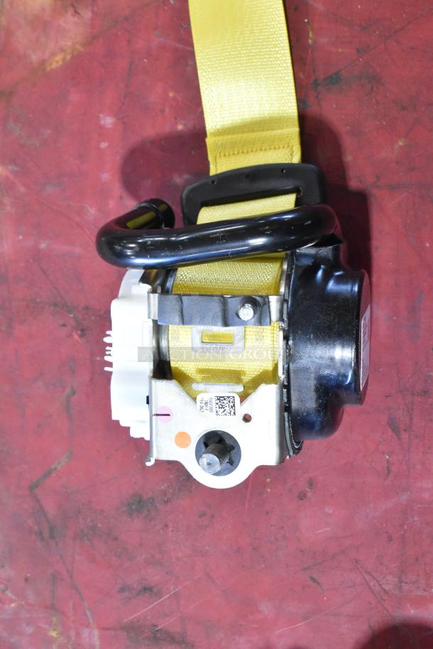 Yellow seat belt mechanism; metal frame, black plastic casing, and QR code tag. Appears unused.